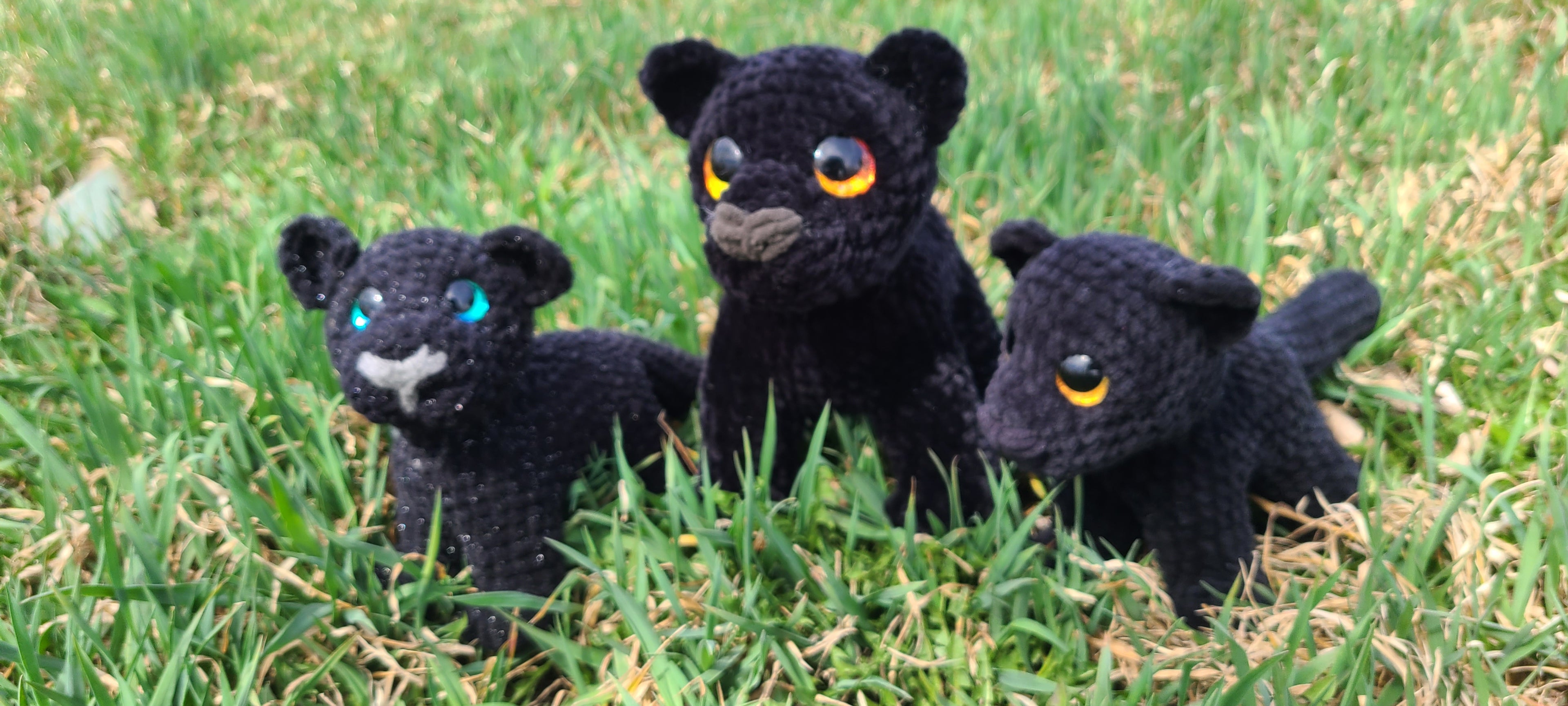 3 crochet panthers in a patch of grass